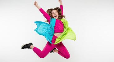 Energetic girl jumping with joy wearing colorful clothes on white background photo