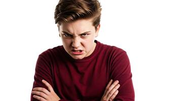 Furious teenage boy with angry expression and crossed arms poses indoors photo