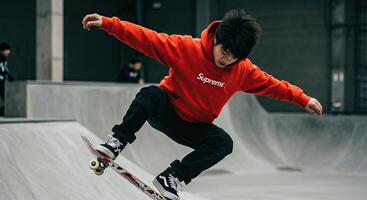 Young Asian man performs skateboard trick in urban skatepark setting photo