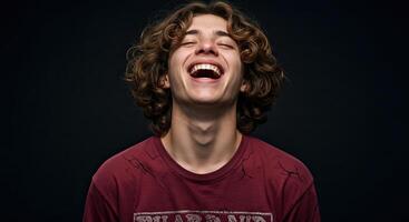 Young man with curly hair laughing joyfully eyes closed studio shot photo