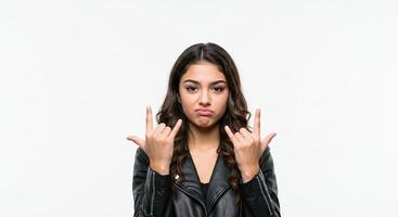 Young woman in leather jacket makes devil horns gesture on white backdrop photo