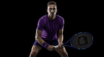 Male tennis player in action pose holding racket with intense focus photo