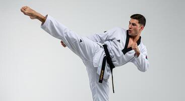 Man in Taekwondo Uniform Executing a Kick with Focus and Determination photo