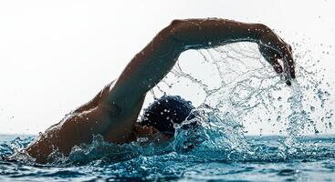 Professional swimmer powerfully strokes through water creating splash effect photo