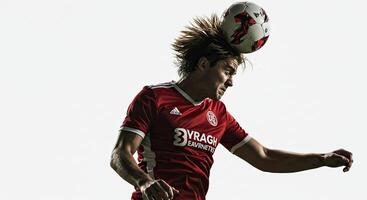 Soccer player heading the ball in action against a bright, clear background photo
