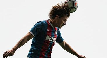 Soccer player heading the ball in a dynamic, action-packed moment against sky photo