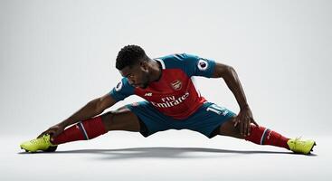 Soccer player stretching in studio wearing Arsenal jersey with a white background photo