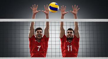 Two determined volleyball players blocking a spike over the net with focus photo