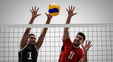 Two male athletes jumping to block a volleyball during a competitive match photo