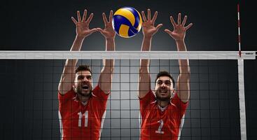 Two male volleyball players jumping to block the ball during an intense match photo