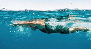 Underwater view of female swimmer gliding through clear ocean water photo