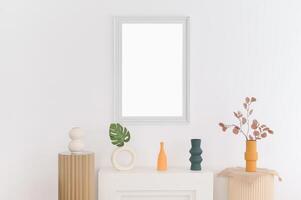 Minimalist interior with decorative vases and dried plants arranged on white surfaces under blank picture frame creating calm atmosphere photo