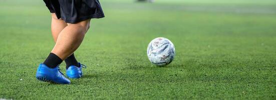 Soccer player legs in blue cleats on green grass field with white ball, showing action and focus during game on sunny day with vibrant colors and clear details photo