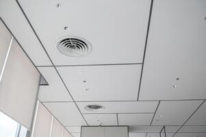 Clean modern office ceiling featuring air vents, recessed lighting, and grid pattern that creates bright and organized atmosphere. design is simple and functional photo