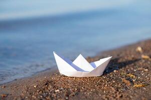 A paper boat on the beach by the water photo