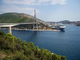 Dubrovnik, Croatia, 08-28-2024, view of Dubrovnik harbor with Franjo-Tudman Bridge suspended in the Adriatic Sea. Viewpoint where you can admire the scenery of the cruise ships and the bridge photo