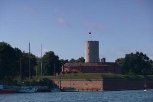 Historical fortress stands majestically by the waterfront with a flag waving in the breeze on a clear day photo