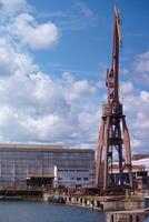 Historic crane by the harbor during a sunny day with scattered clouds in the background photo