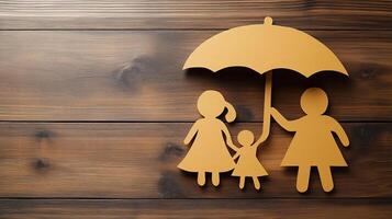 Paper cutout of family with umbrella on wooden background photo