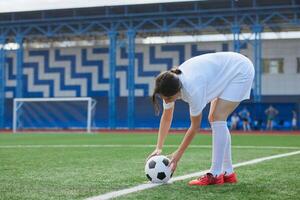 Woman footballer in action, setting ball on turf, preparing to start game. photo