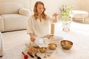 Serene woman using bamboo chime during sound therapy and meditation in cozy minimalist space. photo