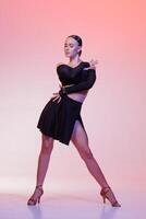 Graceful Latin dancer in stylish black costume posing on colorful pink-lit studio backdrop. photo