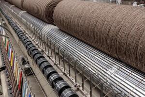 Brown yarn on textile machine in factory, with colorful thread guides and rollers in production. photo