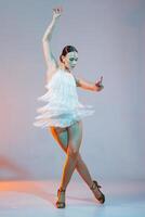Elegant female dancer in fringe dress posing during a Latin performance with dynamic lighting effects. photo