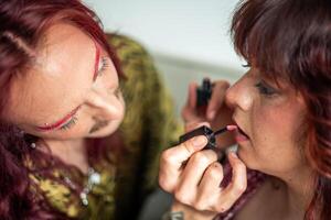 Non-binary person applying lipstick on friend celebrating body positivity photo