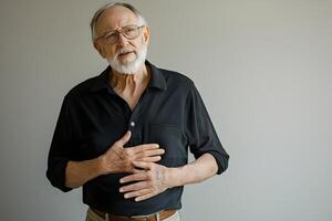 Elderly man expressing emotions while standing against a plain background in a simple setting during daylight hours photo