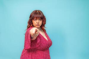 Serious curvy woman pointing finger blaming accusing someone on blue background photo