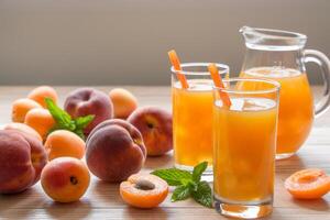 Apricot and peach juice in glasses with ice near the jar of juice and scattered apricots and peaches, mint on a light wooden background. Apricot and peach juice with ice. Horizontal. Daylight. Close. photo