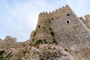 A breathtaking view of ancient castle walls and towering structures, surrounded by fresh green grass under a bright sky, showcasing the charm of historical architecture and tranquil scenic ambiance. photo