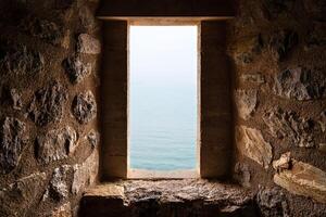 Medieval Stone Window Overlooking Tranquil Aqua Blue Sea on a Sunny Day photo