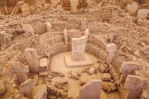 The ancient archaeological site of Gobeklitepe with stone monoliths arranged in a circular pattern, conveying the mysteries of early human construction and culture. photo