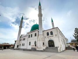 Elegant Islamic Mosque Exterior with Minarets and Green Dome under a Blue Sky photo