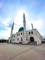 A beautiful mosque with a green dome and four tall minarets under a serene sky, showcasing Islamic architecture and spirituality. photo
