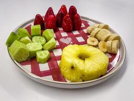Healthy Fruit and Vegetable Mix with Strawberries, Pineapple, and Banana on a Plate photo