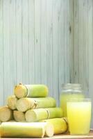 A pile of sugar cane with a glass of juice photo