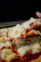 a person is taking a slice of pizza out of a pan photo