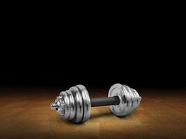 Side view of silver dumbbells placed on wooden floor, black background. photo
