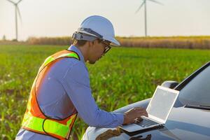 Professional Engineer working on laptop countryside outdoor with wind turbine farm background photo