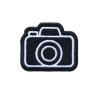 Black and white embroidered patch features camera icon, showcasing simple and stylish design. patch is ideal for clothing or accessories, adding touch of creativity png