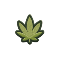 Green embroidered patch in shape of leaf, resembling cannabis leaf, is displayed on plain background. patch features detailed stitching and dark outline png