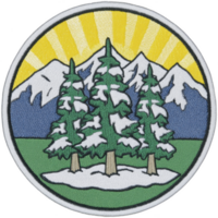 Circular embroidered patch features three snow covered evergreen trees in foreground, set against backdrop of snow capped mountains and bright yellow sunburst sky png