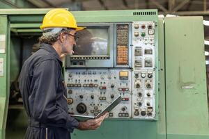 Senior Professional technician engineer operate control heavy industry machine CNC in factory. photo