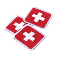 A Red and white embroidered patches featuring cross symbol, often associated with first aid or medical assistance, are displayed transparency background. These patches are square with rounded edges png