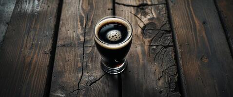 A pint of dark stout presented on weathered wooden planks background. photo