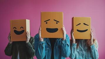 Three cardboard boxes with different facial expressions, held by three people in front of a pink background. photo