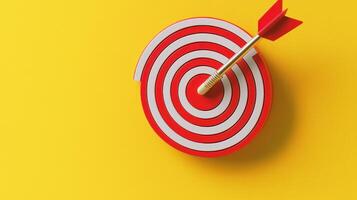 A red dart with a yellow tip is stuck in the center of a red dartboard with a white background. photo